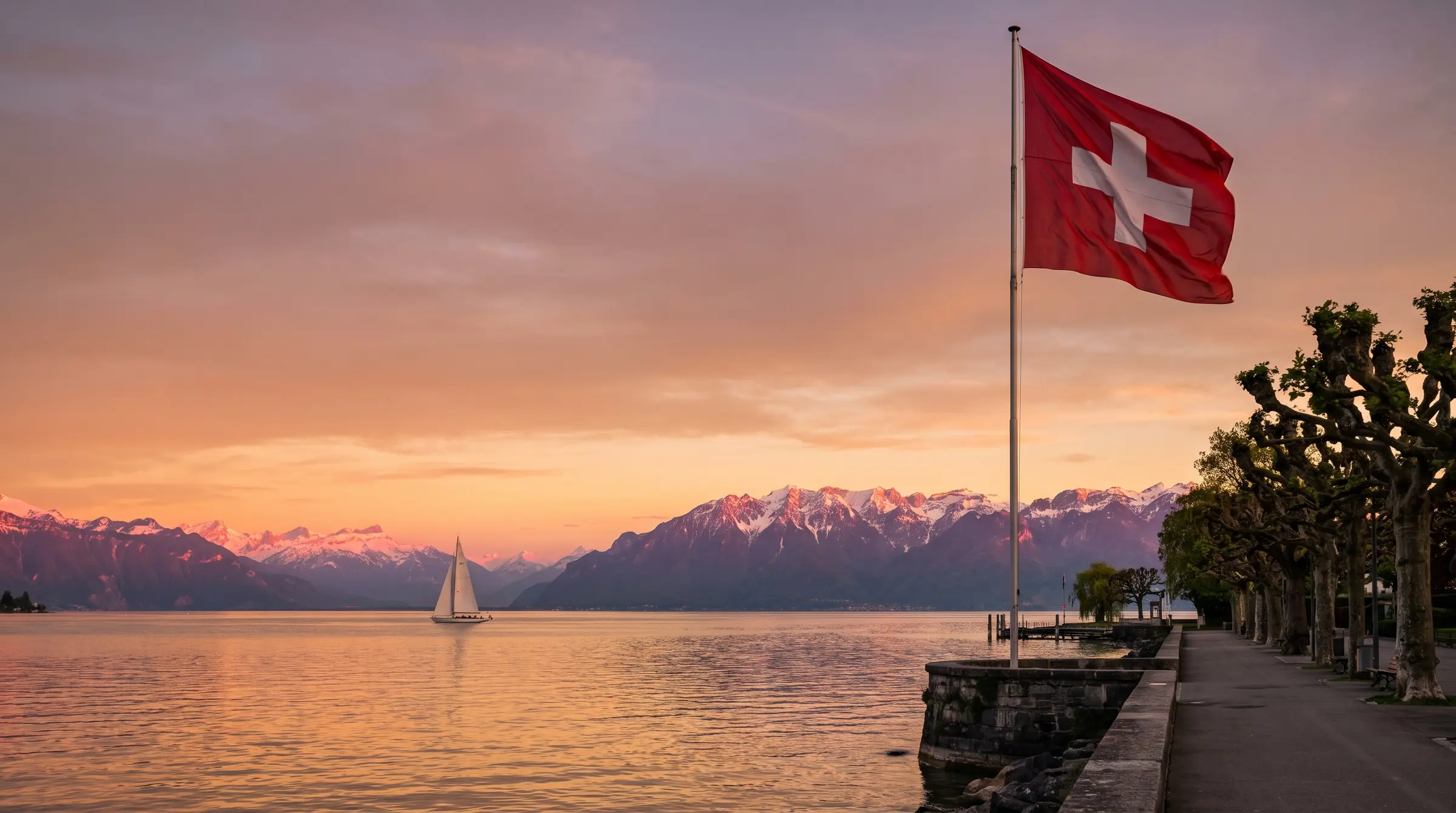 Drapeau suisse sur la promenade au bord du Léman, voilier et Alpes au coucher du soleil