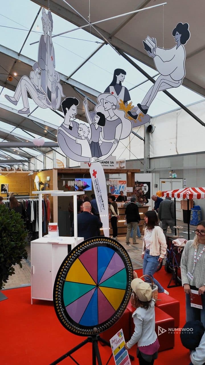 Roue de la chance et illustrations suspendues sur le stand de la Croix-Rouge fribourgeoise, au Comptoir gruérien