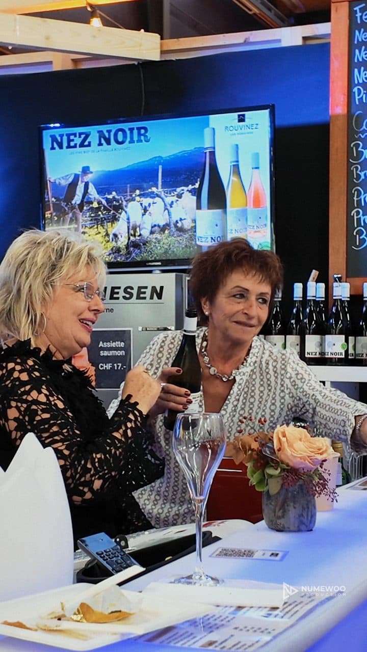 Écran diffusant un concert et ardoise des vins et champagnes servis au verre, sur le stand de La Sirène d'or